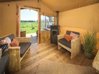 Wood Lodge Cozy: living area with a sofa, an armchair and a stove, with the door open to the terrace