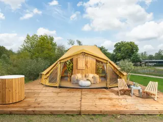 Billy-Joe Double Bell: mustard-colored bell glamping tent on a wooden deck with a hot tub and loungers
