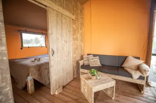 Glamping Lodge 35: bedroom with a double bed and the living area alongside