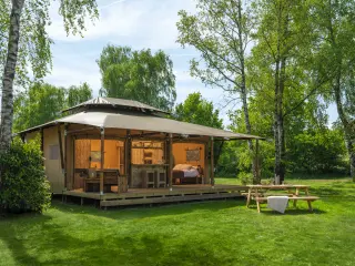 Luxury Suite: canvas pavilion with a wide roof on the grass, with a picnic table in front