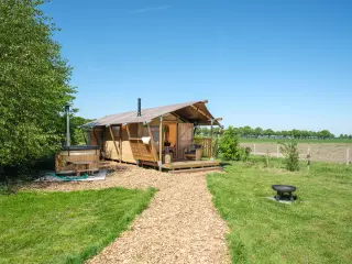 Wood Lodge Cozy: compact glamping tent with a gravel path, a wooden hot tub and a fire pit on the grass