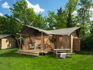 Luxury Safari Lodge: glamping tent on the grass, with a wooden terrace and a picnic table in front
